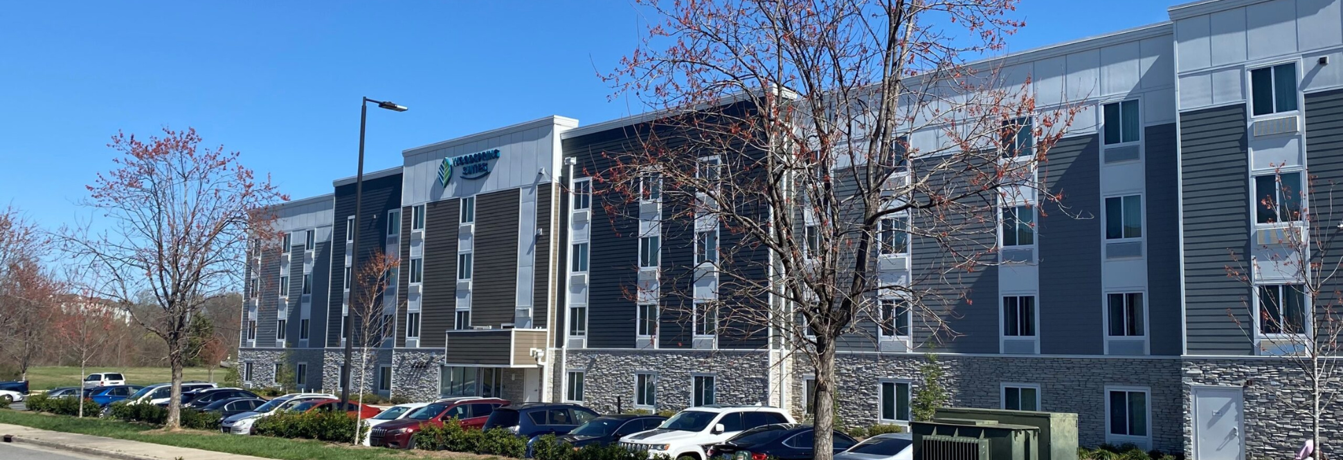 Contemporary four-story hospitality building with organized parking, landscaped frontage, and efficient site circulation.