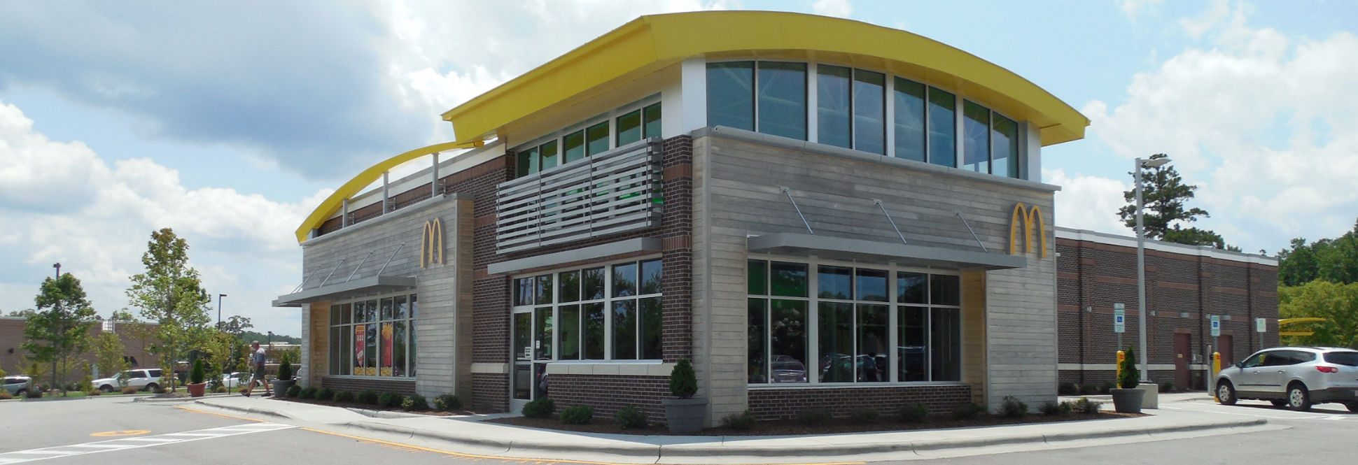 Standalone quick-service restaurant with drive-through, pedestrian access, landscaped perimeter, and urban corner site design.